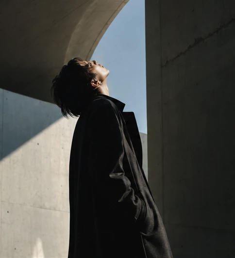 A figure framed by concrete and a pale blue sky
