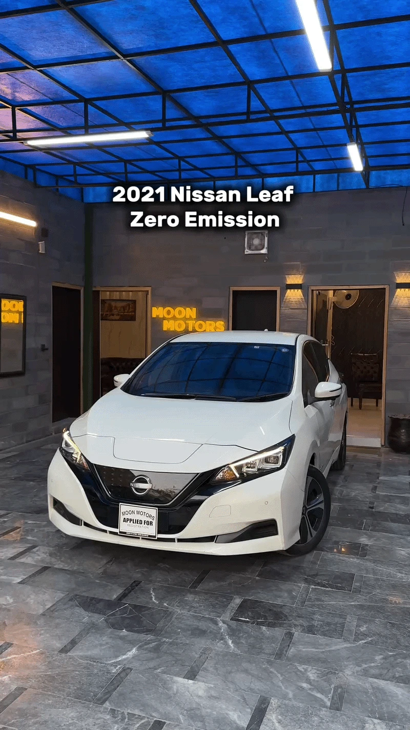 A white Nissan Leaf beneath a blue-lit roof with model information above the car